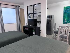 a bedroom with a bed and a television and a kitchen at Lindo y comodo Loft in Hércules