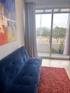 ein blaues Sofa im Wohnzimmer mit großem Fenster in der Unterkunft Lindo y comodo Loft in Hércules