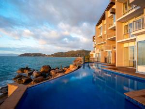 a hotel swimming pool with a view of the water at Grand Mercure Apartments Magnetic Island in Nelly Bay