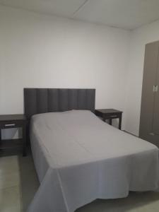 a bedroom with a white bed and two tables at Casa Aramí in Victoria