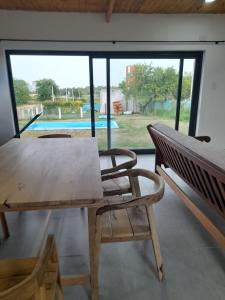 a wooden table and a bench in a room with a pool at Casa Aramí in Victoria