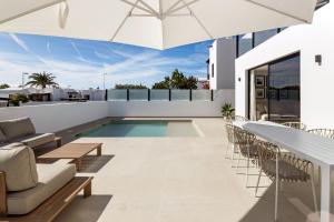 an outdoor patio with a pool and chairs and an umbrella at Villa Sara-Princesa Ico in Tías