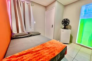 una camera da letto con un letto con una coperta arancione di Pousada Meu Cantinho a Matinhos