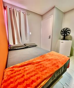 una camera da letto con un letto con una coperta arancione sopra di Pousada Meu Cantinho a Matinhos Altre 14 foto