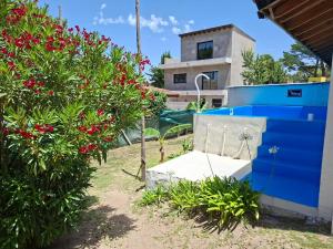 un giardino con fiori rossi e un muro blu di La mary a Villa Gesell