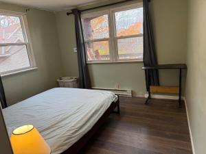 een kleine slaapkamer met een bed en twee ramen bij A fully self-contained one-bedroom apartment in Fredericton