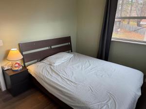 een slaapkamer met een bed, een lamp en een raam bij A fully self-contained one-bedroom apartment in Fredericton