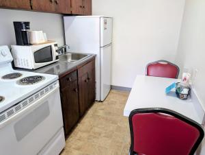een keuken met een witte koelkast en een rode stoel bij Ponderosa Motel in Goldendale
