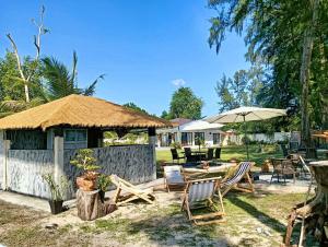 eine Terrasse mit Stühlen, Tischen und einem Sonnenschirm in der Unterkunft Busaba Villa Sea Views in Tha Sala