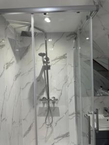 a shower in a bathroom with white marble at A Cosy and Luxurious Studioflat in Navestock