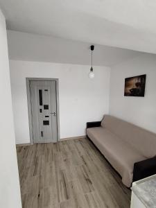 ein weißes Zimmer mit einem Bett und einem Holzboden in der Unterkunft Apartament Alessi Home in Călimăneşti