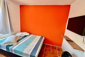a bedroom with an orange wall and a bed at BriSa Do Mar < Flecta Matinhos in Matinhos