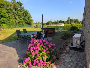 a patio with a table and pink flowers in a garden at Willa Sunny Garden in Sint-Laureins