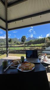 une table avec une assiette de nourriture et un ordinateur portable dans l'établissement Cabaña entre montañas, à Paso Ancho