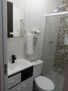 a white bathroom with a toilet and a shower at Studio Campeche in Florianópolis