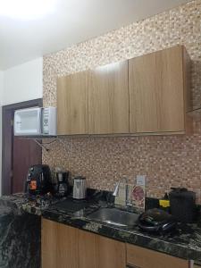 a kitchen counter with a sink and a microwave at Studio Campeche in Florianópolis