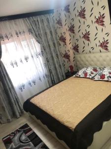 een slaapkamer met een bed en een raam met gordijnen bij Apartament Central in Ploieşti