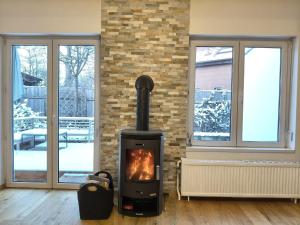 einen Kamin im Wohnzimmer mit zwei Fenstern in der Unterkunft Gemütliches Haus mit Schwedenofen im Wienerwald in Neulengbach + 39 Fotos