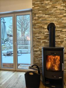 ein Kamin in einem Wohnzimmer mit einer Glasschiebetür in der Unterkunft Gemütliches Haus mit Schwedenofen im Wienerwald in Neulengbach