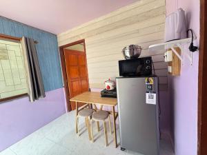 a small kitchen with a table and a refrigerator at Serenity House 4D in Ban Ko Khwan