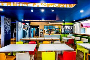 a restaurant with white tables and colorful chairs at ibis Budget Brisbane Airport in Brisbane