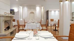 a dining room with white tables and chairs and a fireplace at Akrogiali Exclusive Hotel (Adults Only) in Polychrono +67 photos