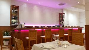 een eetkamer met een bar met paarse verlichting bij Akrogiali Exclusive Hotel (Adults Only) in Polykhrono