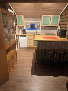a kitchen with wooden cabinets and bar stools at Øse Camping in Gratangen