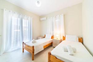 een slaapkamer met twee bedden en een groot raam bij Kalemi House in Kato Korakiana