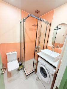 a bathroom with a toilet and a sink and a washing machine at Cosy City-View Flat in Mtatsminda, flat 5 in Itʼkhvisi