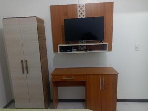 a room with a tv and a desk with a cabinet at Studio Campeche in Florianópolis