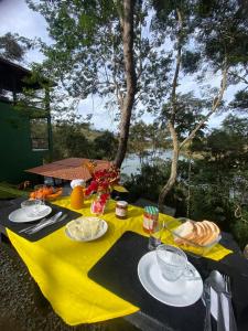 een tafel met een geel tafelkleed met voedsel erop bij Chalé da lagoa in Paraibuna
