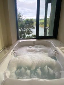 een bad gevuld met water en een raam bij Chalé da lagoa in Paraibuna