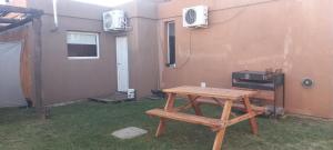 a wooden picnic table in a yard with a stove at El Chalten hospedaje diario in General Pico