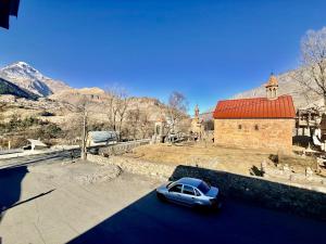 een blauwe auto geparkeerd voor een kerk bij Apartment Once in Kazbegi in Kazbegi