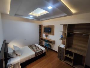 een slaapkamer met een bed, een bureau en een televisie bij Hotel Casa Santiago in Pasto