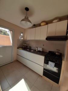 una cucina con mobili bianchi e un forno a piano cottura di Viejo Lobo de Mar a Puerto Pirámides