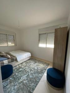 a bedroom with a bed and two blue chairs at Appartement à Skhirat plage in Skhirat