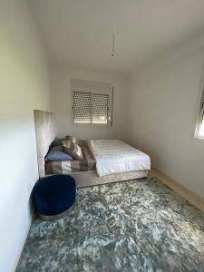 a small bedroom with a bed and a blue chair at Appartement à Skhirat plage in Skhirat +7 photos