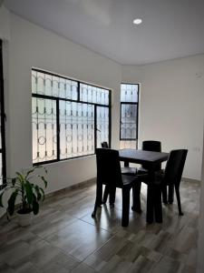 una sala da pranzo con tavolo, sedie e finestre di Tu hogar en Tauramena a Tauramena