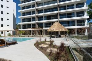 a large building with a swimming pool and a straw umbrella at Spacious 2BR 2BTH El Zonte with oceanview and pool in El Zonte