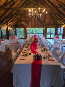 einen langen Tisch in einem Zimmer mit weißen Tischen und Stühlen in der Unterkunft Kruger Island Resort in White River
