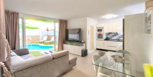 a living room with a couch and a glass table at HEI HEI AND PUA VILLA - heated pool, priv parking, fibre net, Palm-Mar in Palm-Mar