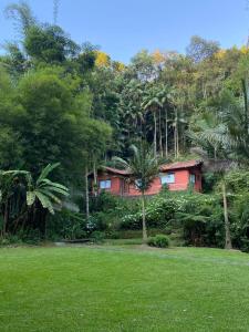een huis midden in een weelderig groen veld bij Havilá Arara Azul in Nova Friburgo