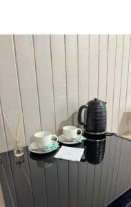 twee koffiekopjes en een waterkoker op een tafel bij Hostal Raizén in Temuco +9 foto's