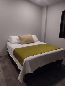 a bedroom with a bed with a green blanket at Calma Place in Carrillo