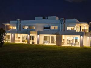 een groot wit huis 's nachts met verlichting bij LS Apart Hotel in Martin Miguel de Güemes International Airport