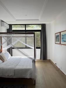 a bedroom with a bed and a large window at Villa Regia in Poponguine