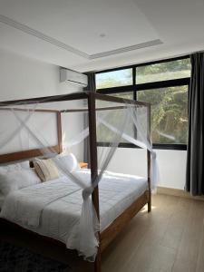 a bedroom with a canopy bed with a large window at Villa Regia in Poponguine