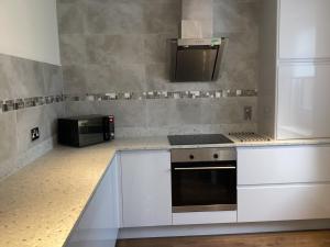 een keuken met witte kasten en een magnetron bij Charlies in Huntly +15 foto's